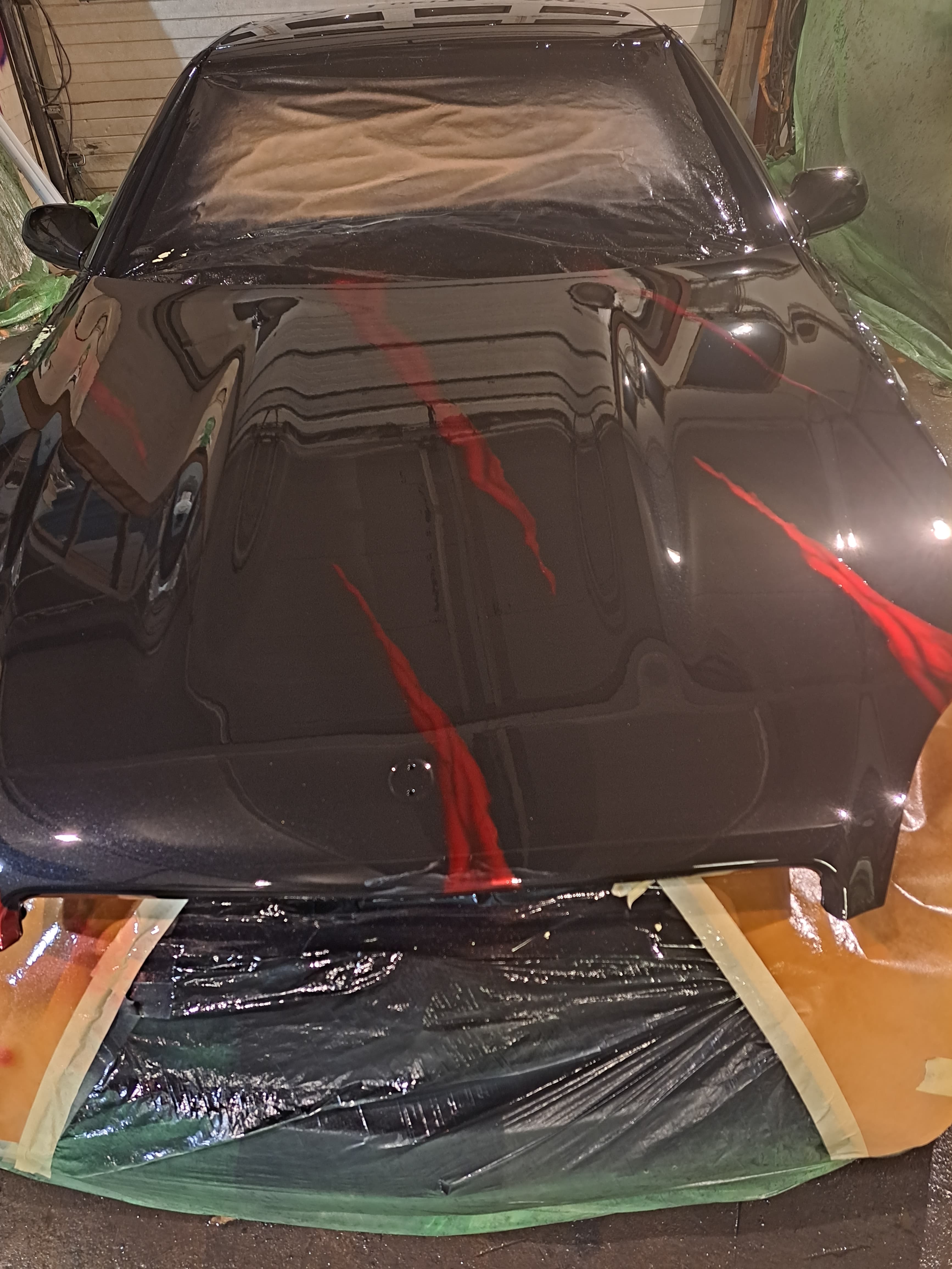 Viimeisteltävä musta auto maalaamossa